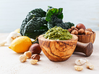 Veggie recipe - homemade pesto with kale and hazelnuts in wooden bowl on marble table with free text space. Healthy concept.