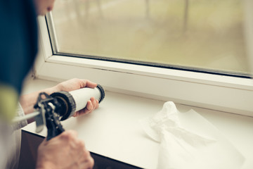 Obraz premium Hands of worker using a silicone tube for repairing of window