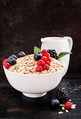 Healthy classic breakfast with granola and various fresh berries on a black surface  with free text space .