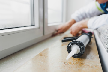 Hands of worker using a silicone tube  for repairing of window