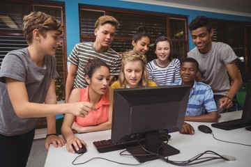 Smiling students studying together in computer classroom
