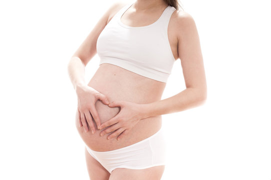 Pregnant woman clasped her hands in a heart shape on the side of the abdomen