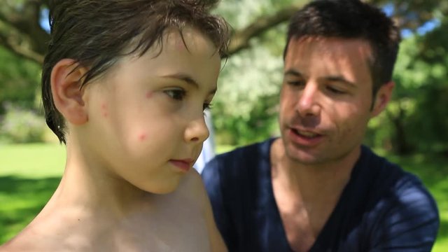 Father putting suncreen to his 6-8 year old child. Parent putting lotion to his kid