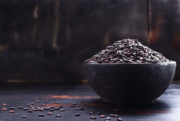 Black rice on black wooden table with free text space. Selective focus.