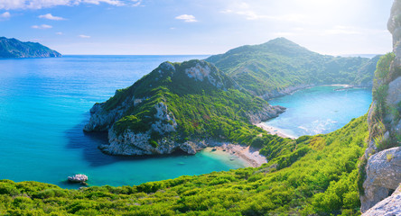 Fototapeta na wymiar Beautiful summertime panoramic seascape. View of the cliff into the crystal clear azure sea bay and distant islands. Unique secluded beach. Agios Stefanos cape. Afionas. Corfu. Greece.
