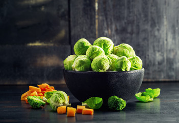 Ingredients Brussels Sprout with Broccoli and carrot on black wooden table. Selective focus