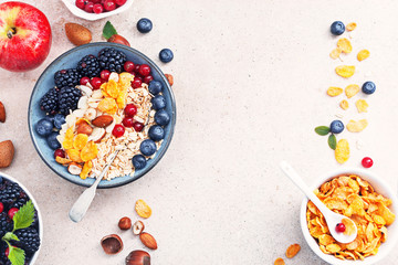 Healthy classic breakfast with oatmeal and various fresh berries,almonds, hazelnuts,coconut and corn flakes on a marble surface, top view, flat lay with free text