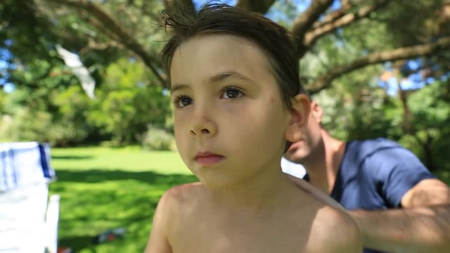 Father putting suncreen to his 6-8 year old child. Parent putting lotion to his kid