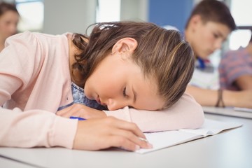 Tired schoolgirl sleeping in classroom - Powered by Adobe