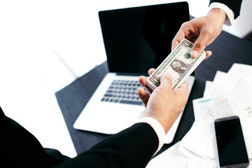 Man offering batch of hundred dollar bills. Hands close up. Venality, bribe, corruption concept....