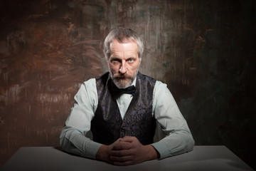 A middle-aged bearded man in a stylish bow tie sitting at a table