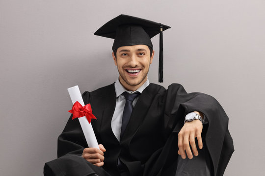 Happy Graduate Student With Diploma Leaning Against Gray Wall