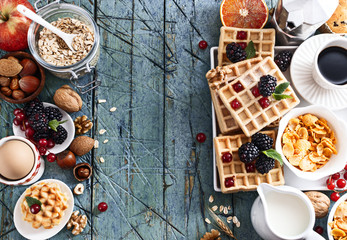 Classic and colorful breakfast  cup of coffee with oatflakes, waffles almond,hazelnuts,various fresh fruits, berries and milk on old wooden table.