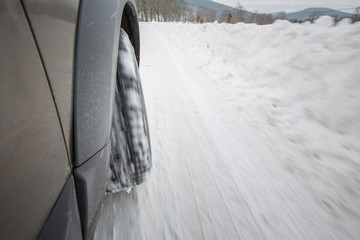 Car with winter tires on a slippery, snowy road - motion blur techinque used to convey movement,...