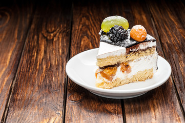 chocolate berry cake slice on plate over brown wooden background