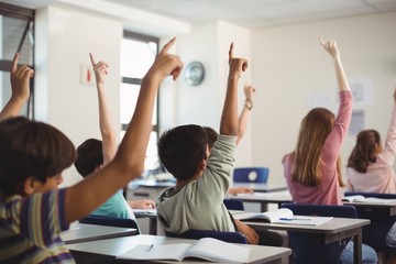 School kids raising hand in classroom - Powered by Adobe