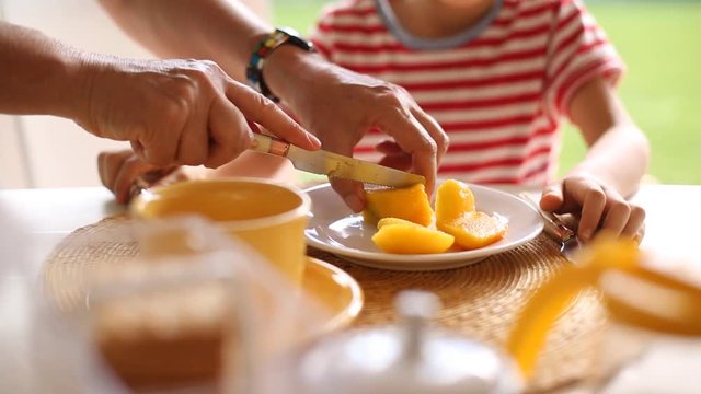 Grandmother slicing peach fruit for her grandson