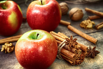 Fresh red and green apples, cinnamon sticks, ground cinnamon, anise stars, walnuts and hazelnuts on an old wooden background © lepatriote