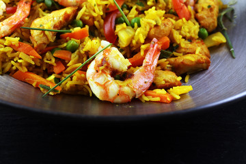 Udon stir-fry rice with shrimp and vegetables in wok pan on black burned stone background