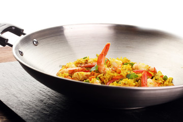 Udon stir-fry rice with shrimp and vegetables in wok pan on black burned stone background