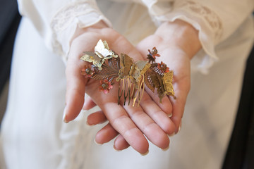 bride hands holding a piece of hair ornament with butterflies