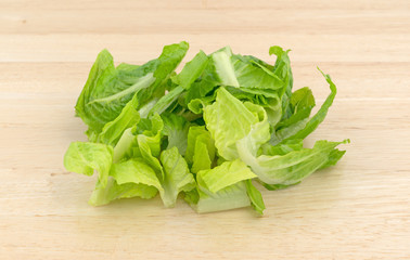 Romaine lettuce that has been sliced on wood cutting board.