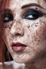 Portrait of young girl with red hair and ground coffee on the face. Photo with art makeup.  Mature woman making cosmetic mask. Face scrub. Beauty concept