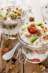 Granola and Greek yogurt in jar. Healthy snack concept. Beautiful rustic wooden background.
