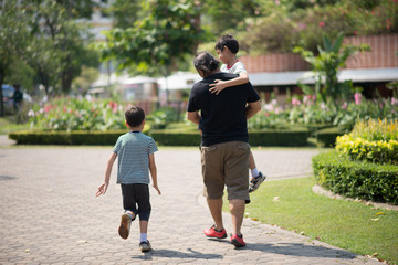 Fototapeta premium Father and sons walking together in the park