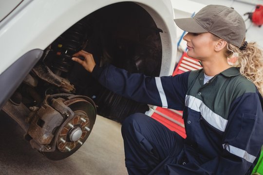 Female mechanic examining a car wheel disc brake