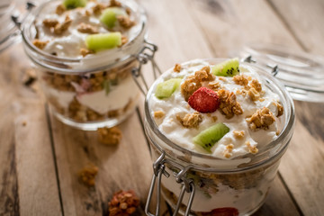 Granola and Greek yogurt in jar. Healthy snack concept. Beautiful rustic wooden background.
