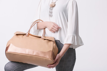 Fashion concept. Clothing and accessories. Woman hands holding beige handbag. Isolated on white background