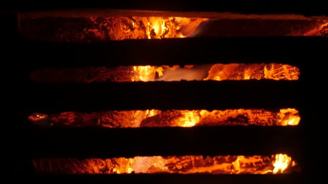 Fire burn behind the  steel grate close-up 4K 2160p 30fps UltraHD footage - Flame spreading arround  burned logs 3840X2160 UHD video