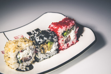 Three sushi on a white plate standing on the white glass 