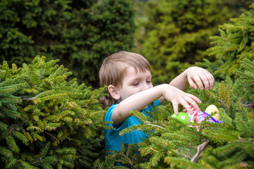 Little boy hunting for easter egg in spring garden on  day. Cute  child with traditional bunny celebrating feast.