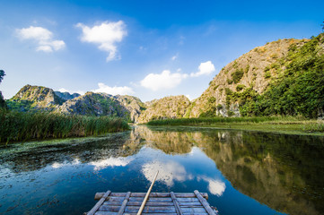 Stunning view of a raft sailing on a beautiful river surrounded by limestone mountains in Ninh...