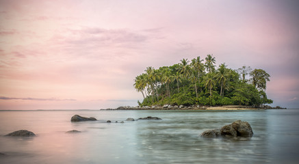 Stunning view of a small island with palm trees and a uncontaminated beach during the sunset in Phuket, Thailand.