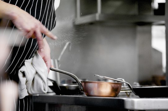 Chef clicking salt into dish during service in working restaurant