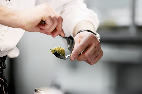 Chef shaping quenell during serice in working kitchen