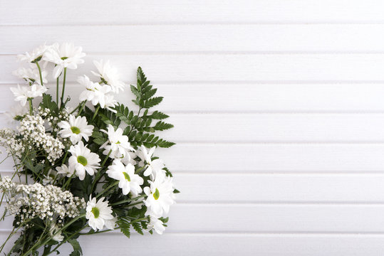 Bouquet from white flowers on white wooden table