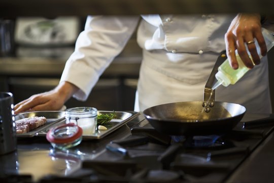 A chef preparing a steak in a commercial kitchen