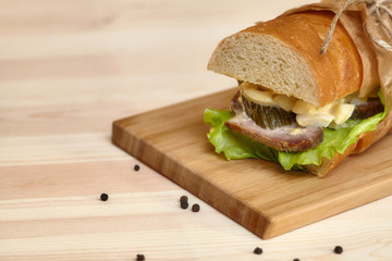 Big sub sandwich baguette with ham on wooden cutting board