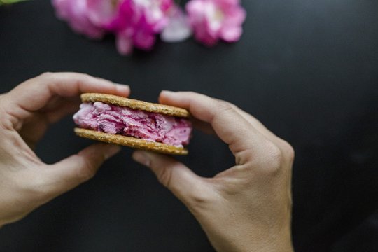 Hände halten Kirscheis-Sandwich mit Waffeln