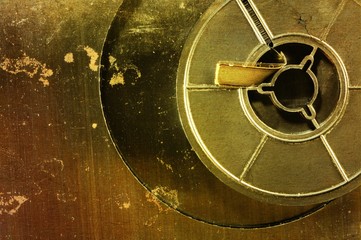 Old film reel on a scratched and rusty metallic background.