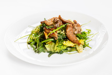 Closeup image of roasted duck at plate with green salad isolated at white background.