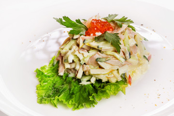 Plate of fresh salad with ham, potato and cucumbers decorated with red caviar isolated at white background.