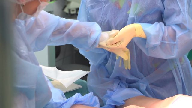 The surgeon wears gloves in the operating room