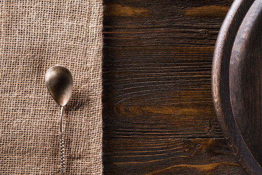 Closeup background of tea spoon at sack cloth and round tray at brown wooden board.