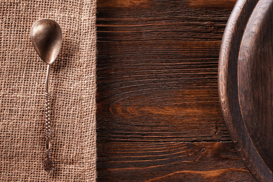 Closeup background of tea spoon at sack cloth and round tray at brown wooden board.