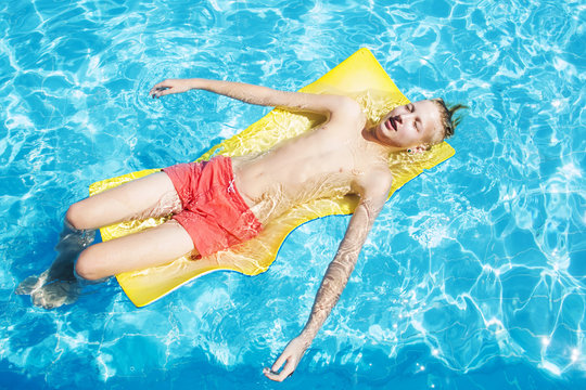 Teenager in red swimming trunks relaxes in the pool